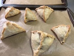 freshly baked samosas on cookie sheet